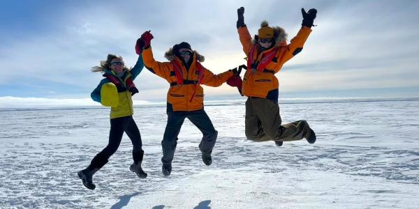 Researchers in Antarctica jumping in the air together