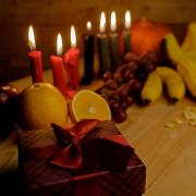 Table with red, green and black candles; fresh fruit and wrapped presents