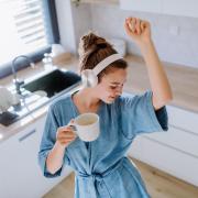 Woman wearing a robe and headphones dancing in her kitchen alone