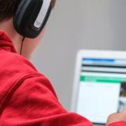 boy wearing headphones and doing school work on a laptop