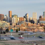 Denver's skyline. The foreground shows cars driving on a highway. 