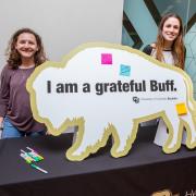 Two campus community members at a Health Promotion booth with a Buffs' gratitude board