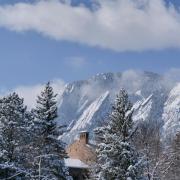 Snow-topped building on campus with Flatirons in the background